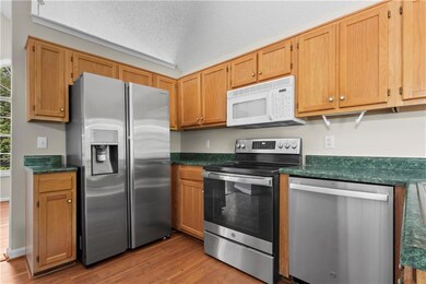 Kitchen featuring appliances with stainless steel finishes, dark countertops, wood finished floors, and a textured ceiling