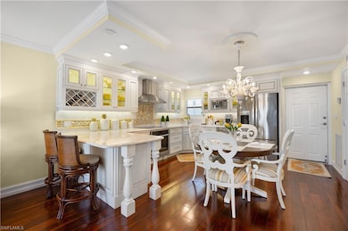 Kitchen featuring a breakfast bar, glass insert cabinets, tasteful backsplash, dark wood-style floors, and stainless steel appliances