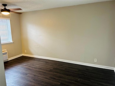 Unfurnished room featuring ceiling fan, dark wood