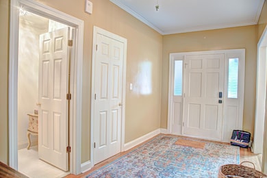Foyer with crown molding and light wood-type flooring