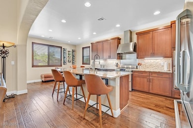 Kitchen featuring light stone countertops, stainless steel appliances, brown cabinetry, a kitchen breakfast bar, and recessed lighting