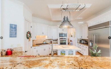 Kitchen featuring white cabinets, backsplash, sink, built in appliances, and ornamental molding