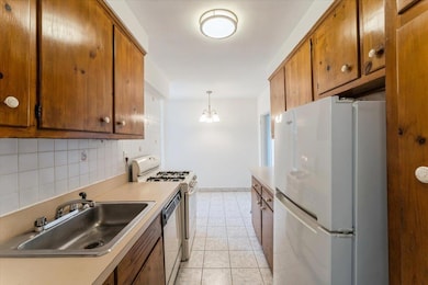Kitchen with white appliances, a sink, brown cabinets, tasteful backsplash, and a chandelier