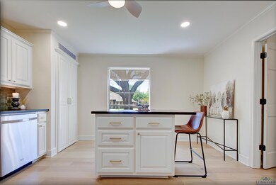 Kitchen with stainless steel dishwasher, dark countertops, and light wood-type flooring