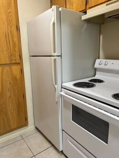 Kitchen featuring light tile patterned floors, range, and exhaust hood