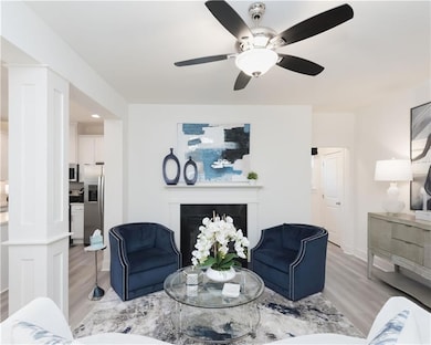 Living room with light wood-type flooring, a fireplace, and ceiling fan
