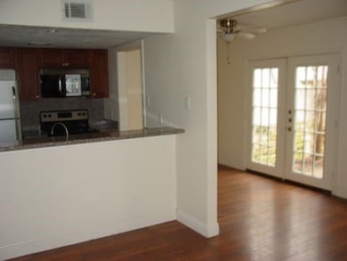 Kitchen with stainless steel electric stove, black microwave, dark wood-type flooring, french doors, and freestanding refrigerator