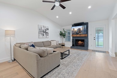Living room with a stone fireplace, a ceiling fan