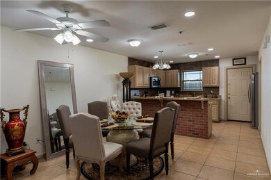 Tiled dining space featuring ceiling fan with notable chandelier