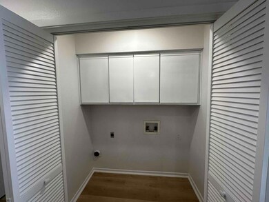 Clothes washing area featuring wood finished floo