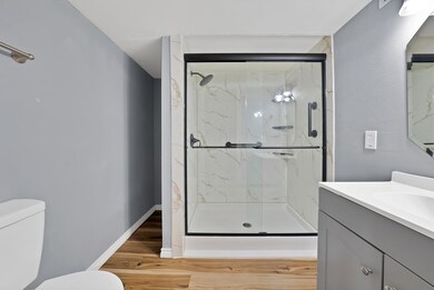 Full bath with vanity, a marble finish shower, and light wood finished floors
