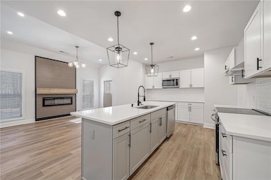 Kitchen featuring backsplash, light wood-style flooring, stainless steel appliances, and a sink