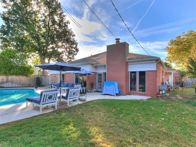 Back of property featuring brick siding, a patio, a fenced backyard, and a chimney
