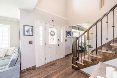 Entryway with dark wood-style floors, crown molding, stairway, and a high ceiling