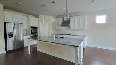 Kitchen with appliances with stainless steel finishes, white cabinets, tasteful backsplash, hanging light fixtures, and recessed lighting