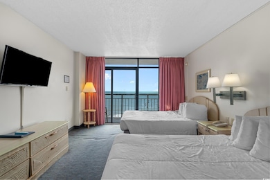 Bedroom with a wall of windows, a water view, access to exterior, carpet flooring, and a textured ceiling
