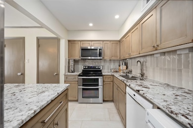 Bright and functional kitchen featuring recessed lighting, granite counters, abundant cabinetry, and a stylish backsplash. Stainless steel appliances include a smooth-top double oven range and built-in microwave.