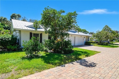View of front of property featuring a front yard, decorative driveway, a standing seam roof, a metal roof, and stucco siding