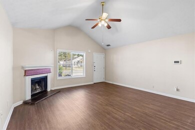 Unfurnished living room with dark wood-style floors, a fireplace with raised hearth, a ceiling fan, and high vaulted ceiling