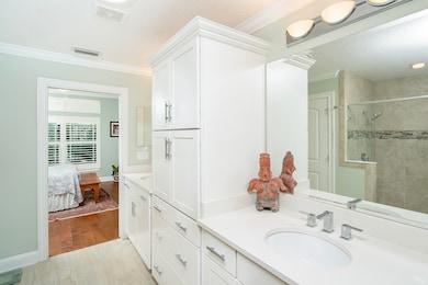 Bathroom with vanity, crown molding, light wood-type flooring, tiled shower, and a textured ceiling