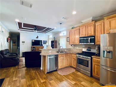 Kitchen featuring ceiling fan, kitchen peninsula, dark wood-type flooring, appliances with stainless steel finishes, and sink
