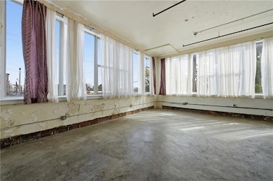 Spare room featuring healthy amount of natural light and unfinished concrete flooring