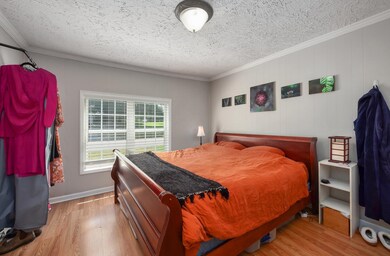 Bedroom featuring wood finished floors, crown molding, and a textured ceiling