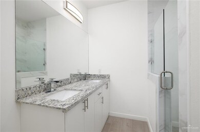 Bathroom featuring wood-type flooring, double sink, vanity with extensive cabinet space, and an enclosed shower