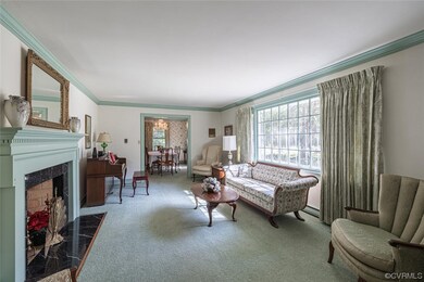 Carpeted living room with a tiled fireplace, crown molding, and a baseboard radiator