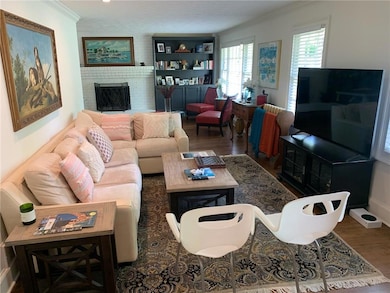 Living room with wood finished floors, crown molding, and a brick fireplace