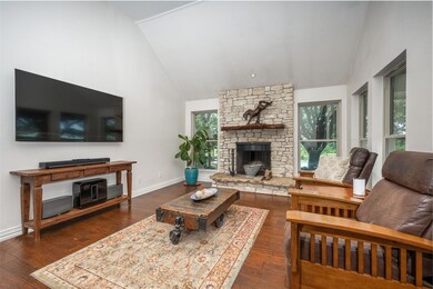 Living room with a healthy amount of sunlight, dark wood-type flooring, and a stone fireplace