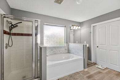 Bathroom with a shower stall, a garden tub, and light wood-style flooring