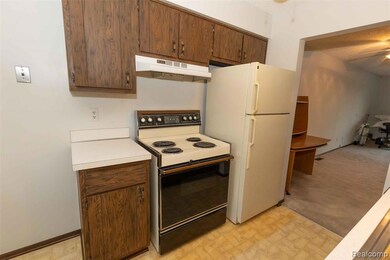 Kitchen with electric stove, light countertops, under cabinet range hood, light flooring, and dark brown cabinetry
