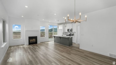 Unfurnished living room featuring light wood-style floors, recessed lighting, a chandelier, and a glass covered fireplace