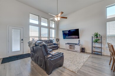 Living room with a towering ceiling, light wood finished floors, and ceiling fan