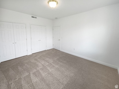 Unfurnished bedroom featuring carpet and two closets