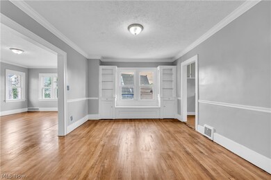 Empty room featuring a textured ceiling, ornamental molding, and light hardwood / wood-style flooring