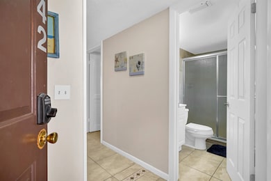Full bathroom featuring light tile patterned flooring, a stall shower, a closet, and a textured ceiling