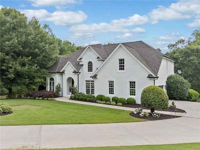 French country inspired facade featuring a front yard, roof with shingles, and brick siding