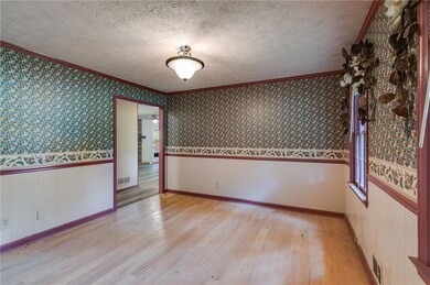 Spare room featuring crown molding, light wood-style flooring, a textured ceiling, a wainscoted wall, and wallpapered walls