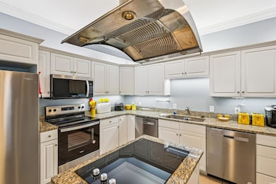Kitchen with appliances with stainless steel finishes, island exhaust hood, a sink, crown molding, and white cabinets
