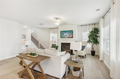 Living area featuring a glass covered fireplace, light wood finished floors, and a ceiling fan