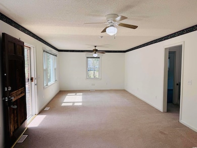 Spare room featuring light colored carpet, visible vents, a textured ceiling, and a ceiling fan