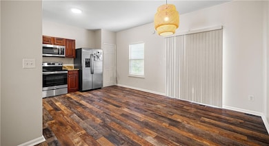 Kitchen featuring stainless steel appliances, dark wood-type flooring, and hanging light fixtures