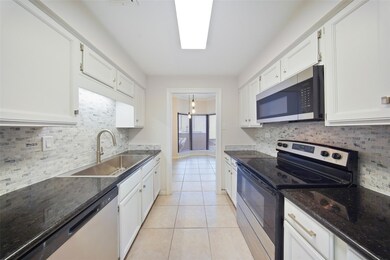 Bright galley kitchen with sleek granite counters, stainless steel appliances, and modern backsplash leading into the breakfast nook.