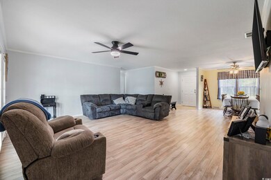 Living room with ceiling fan, crown molding, and l