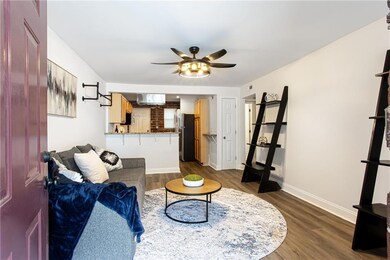 Living area with a ceiling fan, dark wood-style floors, and baseboards