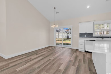 Kitchen featuring white cabinetry, plenty of natural light, light wood finished floors, pendant lighting, and high vaulted ceiling