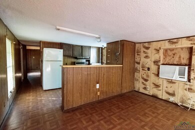 Kitchen featuring freestanding refrigerator, wooden walls, a textured ceiling, a peninsula, and cooling unit