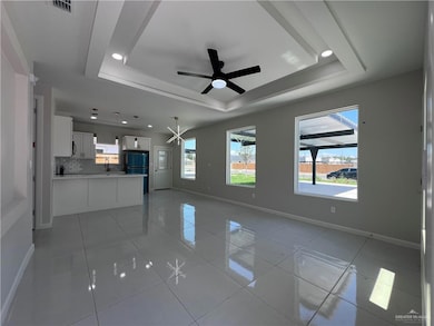 Unfurnished living room featuring a tray ceiling, a ceiling fan, light tile patterned flooring, and recessed lighting